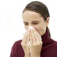 Foto de una mujer estornudando porque tiene influenza estacional.