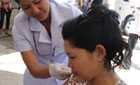 Woman receives seasonal flu vacccination from female nurse in Laos