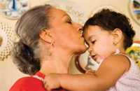 Photo of senior woman kissing a young child.