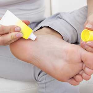 Woman applying cream to her foot.