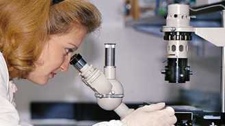 Image of scientist looking in a microscope.