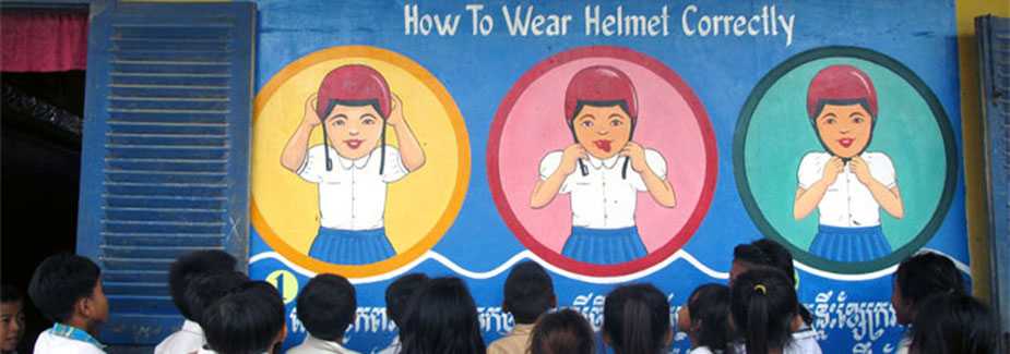 	Children looking at a mural that shows how to wear a motorcycle helmet correctly.