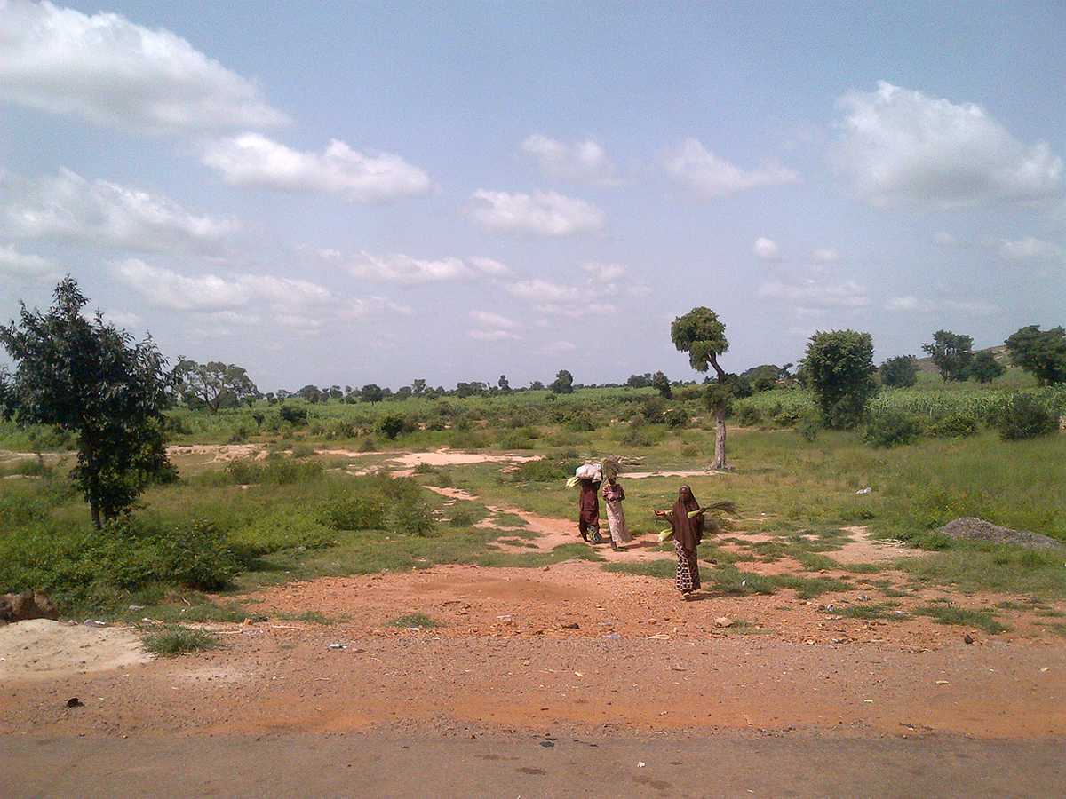 Despite being able to see far into the distance because of the open landscape in Nigeria, at times, it is still not possible to locate all communities. In this picture, vaccinators follow a family traveling in the remote area of Sokoto, Nigeria to vaccinate children. 