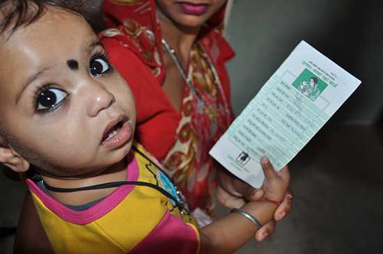 	A child holding his vaccination card at a health facility in Rajasthan, India. Courtesy of Steve Stewart/CDC.