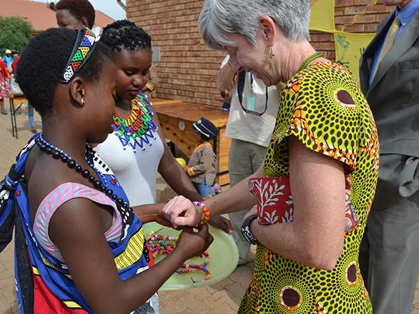Dr. Nancy Knight receives a “welcome” bracelet from children, caregivers, and site staff, at CDC-funded orphans and vulnerable children (OVC) site, Sithandizingane, in Ekurhuleni, Gauteng, Friday October 2, 2015.