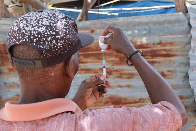 Animal health worker in Haiti preparing to administer a rabies vaccine to a dog.