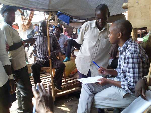 Dr. Benon Kwesiga (r) conducts interview in Disableds Market