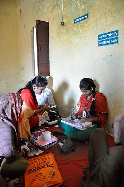 Social Health Leader measuring blood pressure and recording ECG in Mhotarwadi village, Maharashtra state, India.