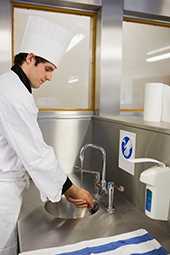 a food service worker or chef washing his hands at a basin