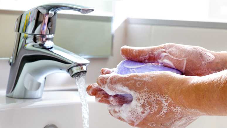 Washing hands under a faucet with soap and water