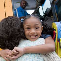 Photo: Girl hugging her Mom by the school bus