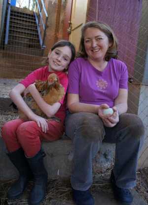 Mother and Daughter sit and hold a chicken