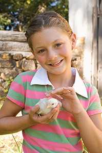A girl holds a chick. Photo