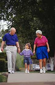 Grandparents and granddaughter (4-5) walking on sidewalk