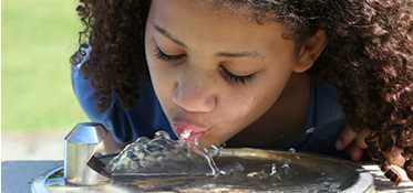 	Young girl drinking form water fountain