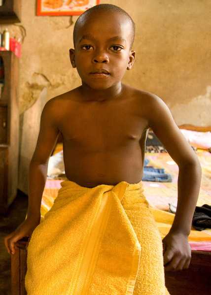 	a little boy in the developing world sitting in a clinic awaiting examination