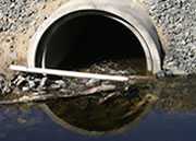 	A sewer system pipe opening, along with the dirty water coming out of it