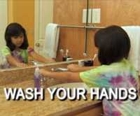 a girl washing her hands with soap at the sink.