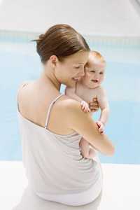 Mother holding baby by the side of the swimming pool