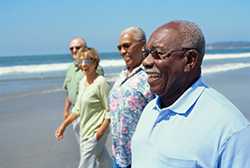 photo of four older people walking on a beach