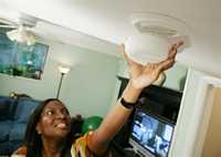 photo of a woman installing a smoke detector