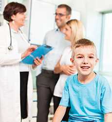 Child smiling, doctor talking to parents in background
