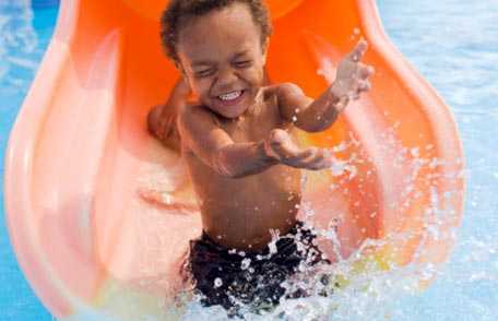 	boy sliding into pool at a recreational water park