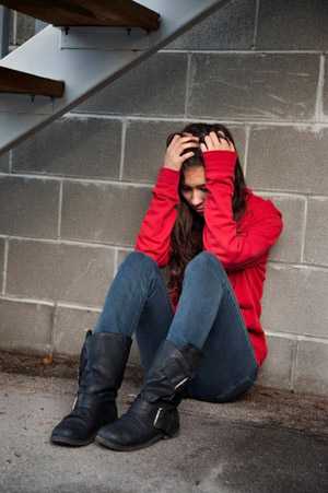 a teen girl sitting with her head in her hands