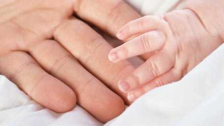 closeup of a baby's hand touching an adult's hand