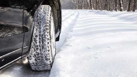 closeup of a car's front tire on a snow-covered road