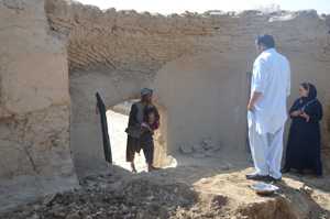 Photo: A man holding his baby outside his home in a very rural area of Afghanistan
