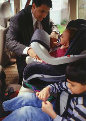 Photo: Father fastening seatbelts on his children