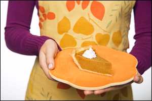 A woman holds a pumpkin pie