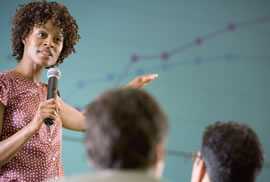 woman holding a microphone speaking to a group