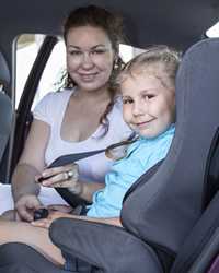 Photo: mom buckling daughter into booster seat