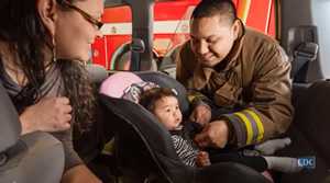	photo: fireman helping Native American mother with her childs car seat.