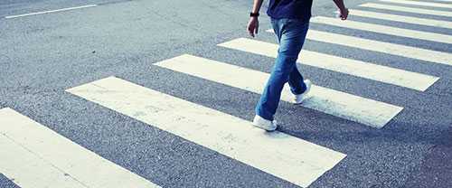Photo: man in jeans walking across a zebra crossing 