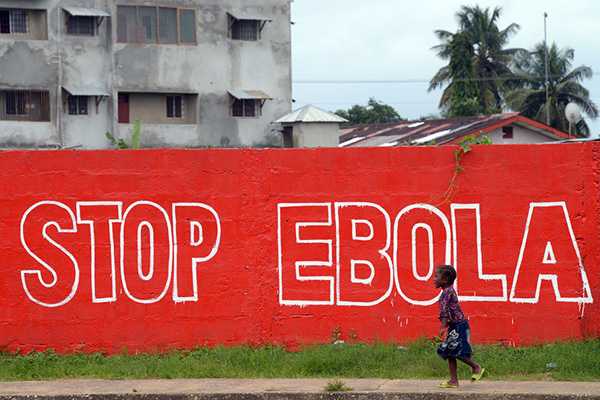 A child in Liberia walks by a Red Sign that says 
