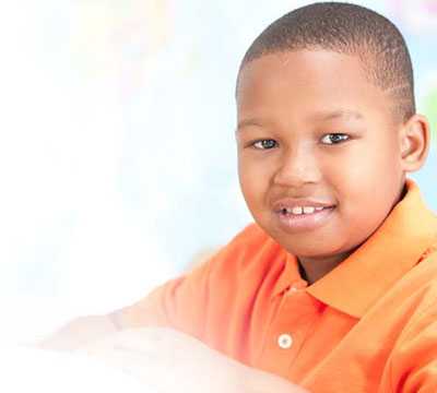 A young african american boy in an orange shirt