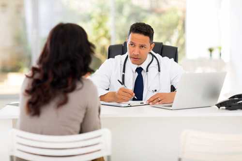 Doctor at his desk talking to a woman