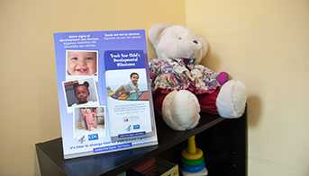 Act Early Materials on a shelf with a teddy bear and toys