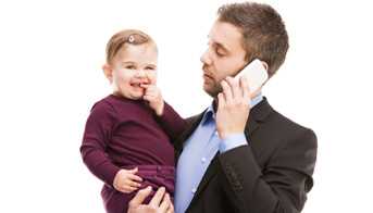 Man talking on phone holding baby.