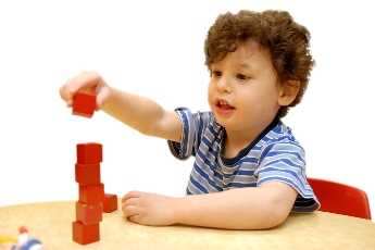 Photo: Child playing with blocks at table