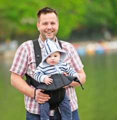 Dad carrying a baby in a harness.