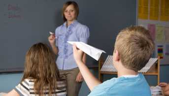 Boy throwing a paper airplane in a classroom