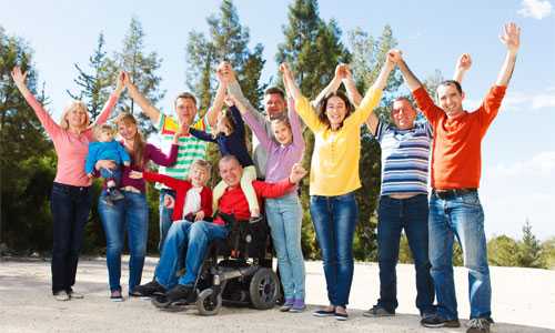 Foto de un hombre discapacitado en una silla de ruedas al aire libre con su familia.
