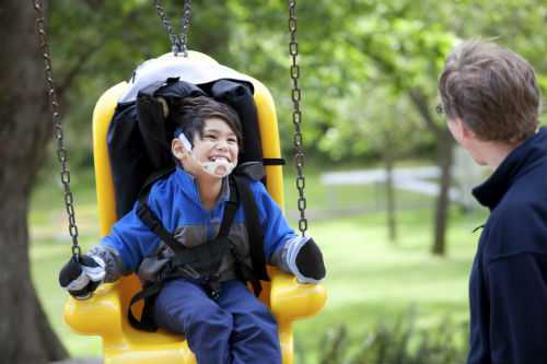 Photo of disabled child on swing with father