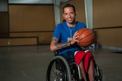 Hombre en silla de ruedas con un balón de baloncesto en un gimnasio