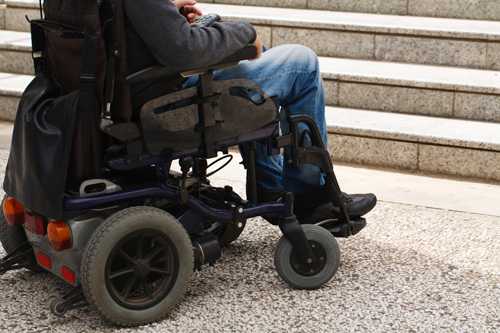 Persona en silla de ruedas al comienzo de las escaleras