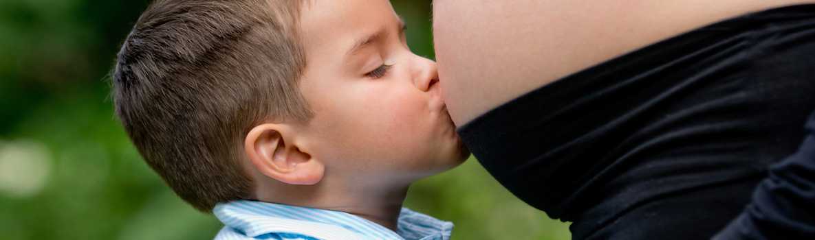 Little boy kissing his mom's pregnant belly.